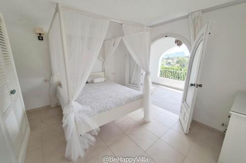 een witte slaapkamer met een hemelbed bij BeHappyVilla in Benissa
