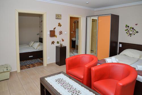 a bedroom with a bed and two red chairs at Major Panzió és Étterem in Hajdúszoboszló