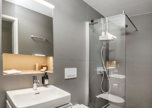 uma casa de banho com um chuveiro, um lavatório e um espelho. em ※Luxus Loft mit Boxspringbetten und Heimkino ※ em Inzlingen