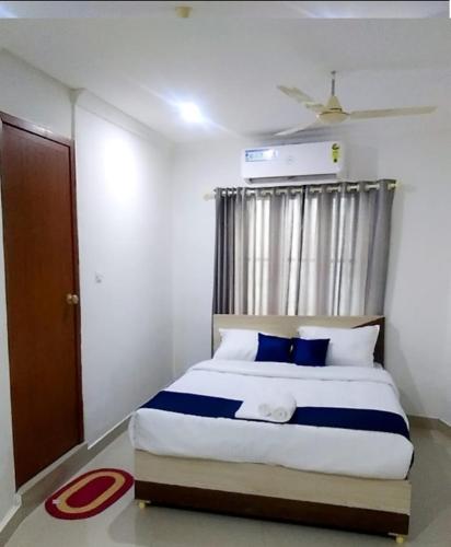 a bedroom with a bed with blue pillows and a window at Tharavad Residency in Iritti