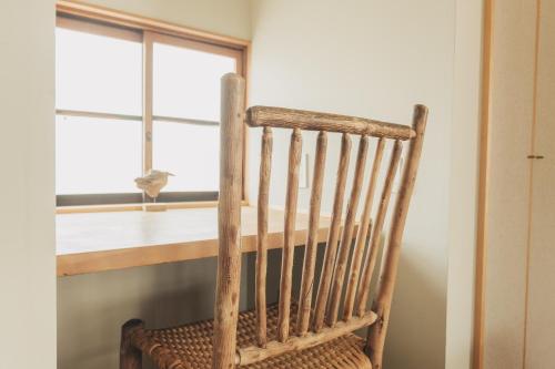a wooden chair in front of a table with a window at Une stay&diner in Sasayama