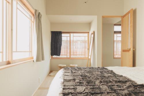 a bedroom with a bed and two windows at Une stay&diner in Sasayama