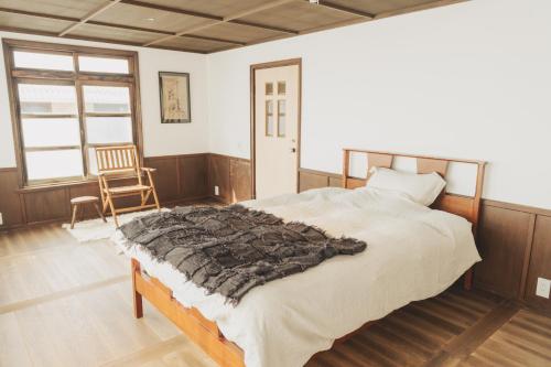 ein Schlafzimmer mit einem großen Bett und einem Stuhl in der Unterkunft Une stay&diner in Sasayama