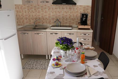 a kitchen with a table with plates and flowers on it at CasApulia - Bari Airport apartment in Bitonto