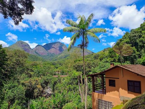 a palm tree in front of a house with mountains in the background at Casa Fofa! No Coração de Araras! in Araras Petropolis