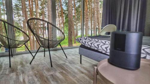 a bedroom with a bed and two chairs and windows at GaujaClub - our BOSE and Bang&Olufsen lofts on a lake in Gauja