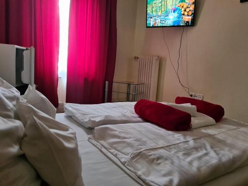 a bedroom with two beds with red and white sheets at Hotel Oroszlán Szigetvár in Szigetvár