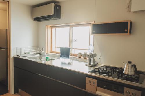 a kitchen with a stove and a sink and a window at Une stay&diner in Sasayama