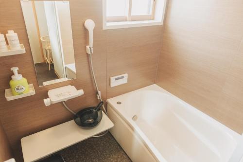 a bathroom with a white tub and a mirror at Une stay&diner in Sasayama