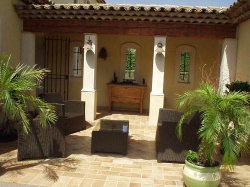 a courtyard of a house with chairs and palm trees at Chambre d'hôtes "La Bastide des Eucalyptus" in Antibes