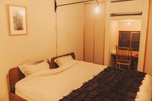 a bedroom with a bed and a table and a chair at Une stay&diner in Sasayama