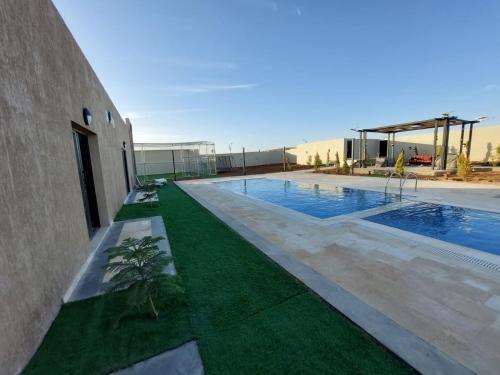 a swimming pool with grass next to a building at Giving Paradise Chalet in Amman