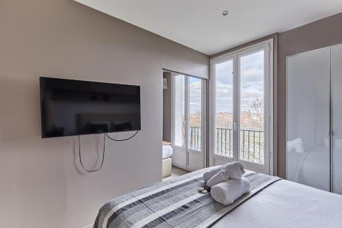 un osito de peluche sentado en una cama en un dormitorio en Appartement Rolland Garros, Parc des Princes by Studio prestige, en Boulogne-Billancourt