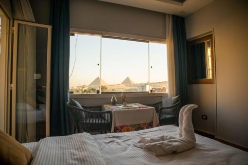 a bedroom with a bed and a table and a window at Egipto Tut Ankh Amon pyramids view- foreiigners only in Cairo