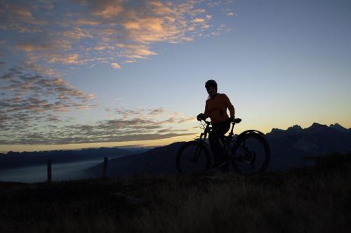 a man riding a bike on a hill at sunset at Pension Panorama in San Lorenzo di Sebato