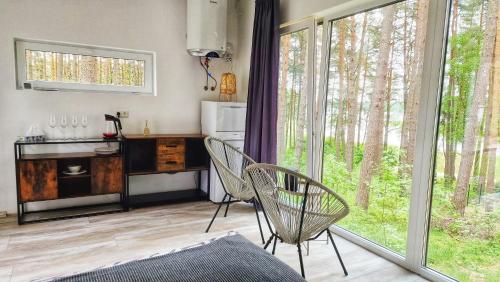 a living room with two chairs and a kitchen with windows at GaujaClub - our BOSE and Bang&Olufsen lofts on a lake in Gauja
