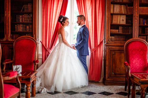 a bride and groom standing next to a window at Château des Monthairons Hôtel Restaurant GastroMaison Spa privatif in Les Monthairons