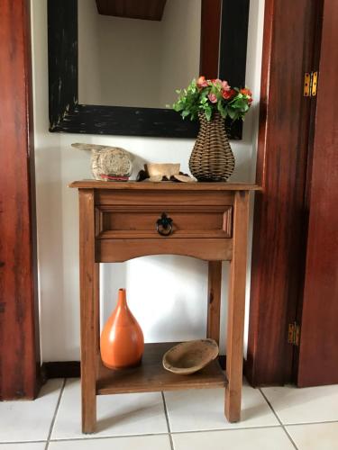 uma mesa de madeira com um vaso de flores em Sobrado,Armação -Sul da Ilha-Floripa em Florianópolis
