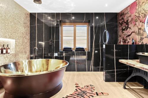 a bathroom with a large tub and black tiles at Normanton Park House - Luxury Rutland Water Home in Oakham