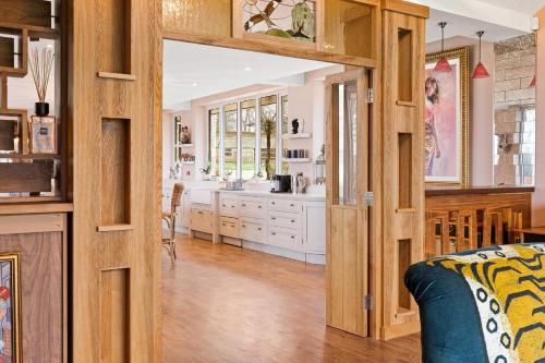 a kitchen with wooden walls and a living room at Normanton Park House - Luxury Rutland Water Home in Oakham