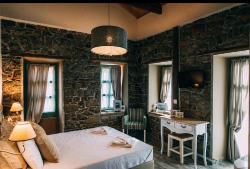 Schlafzimmer mit einem Bett, einem Schreibtisch und Fenstern in der Unterkunft Axiokersa Suites in Samothráki
