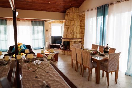 sala de estar con mesa, sillas y chimenea en ATLAS Villa, en Kástro Tornéze