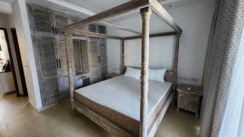 ein Schlafzimmer mit Himmelbett und Fenster in der Unterkunft Diani Beachfront Flats in Ukunda