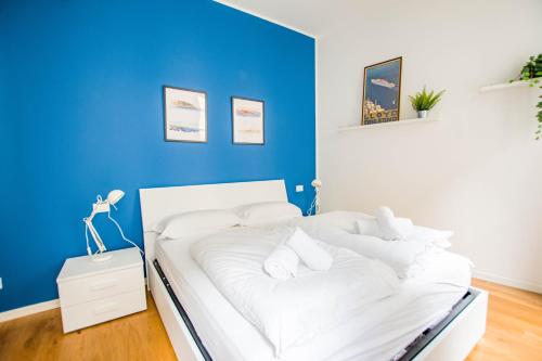 een wit bed in een kamer met een blauwe muur bij G10 in Trieste