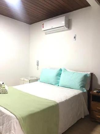 a bedroom with a bed with blue pillows and a window at Sentinelas do Mar in Arraial do Cabo