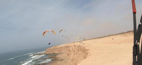 een groep mensen die vliegeren op het strand bij Atlanticguesthouse in Douaïra