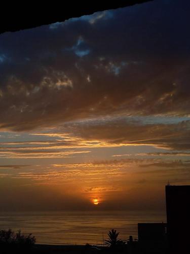 una puesta de sol sobre el océano con el sol en el cielo en Atlanticguesthouse, en Douaïra