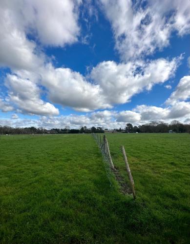 a fence in a field under a cloudy sky at Little Hill Farm Villa in Ringwood
