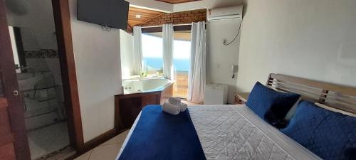 a bedroom with a bed and a tub and a window at Sentinelas do Mar in Arraial do Cabo