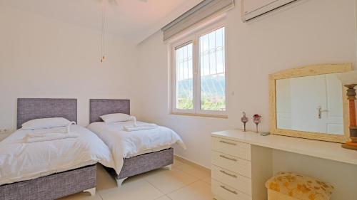 Un dormitorio con dos camas y un tocador y un espejo. en Villa Estelle, en Fethiye