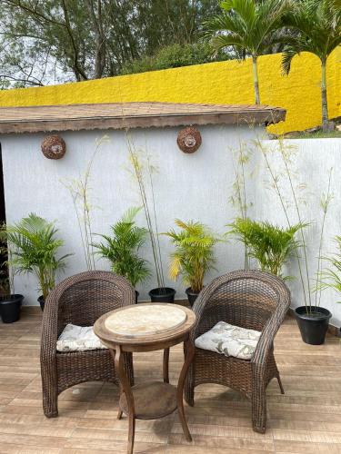 two wicker chairs and a table on a patio at Sentinelas do Mar in Arraial do Cabo