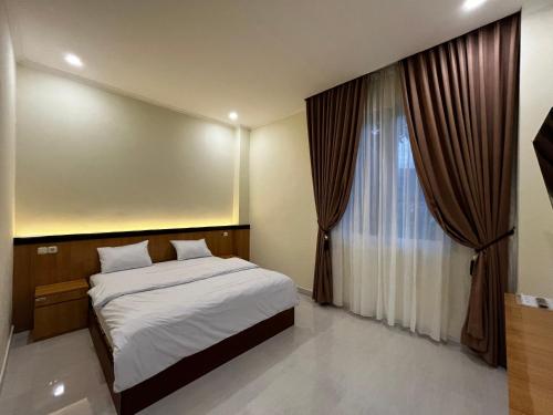 sypialnia z łóżkiem i oknem z zasłonami w obiekcie Penginapan Jangkar w Luwuk