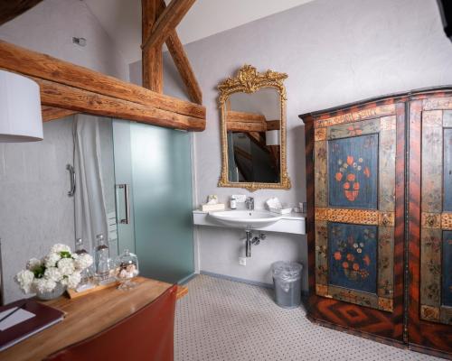 a bathroom with a sink and a wooden cabinet at Romantik Hotel de L'Ours in Sugiez