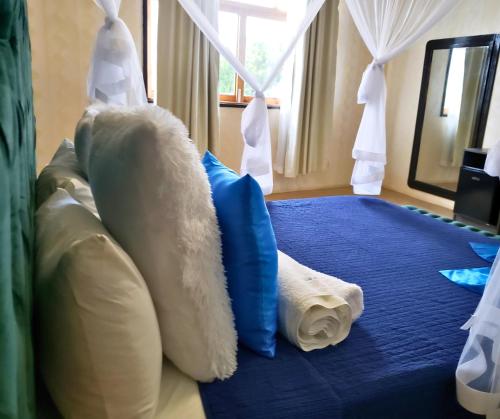 Habitación con cama con almohadas azules y blancas. en Galo do Mar en Maputo