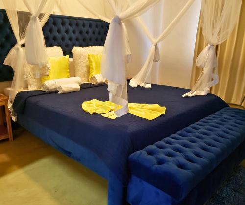 a blue bed with yellow pillows and curtains at Galo do Mar in Maputo