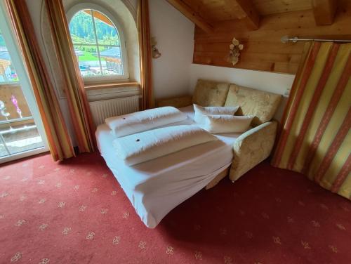 a bedroom with a bed and a couch and a window at Hotel Gut Kramerhof in Kirchdorf in Tirol