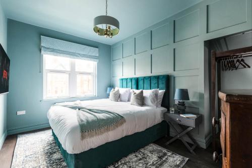 a blue bedroom with a bed and a window at Emerald Park - with Games Room in Scarborough