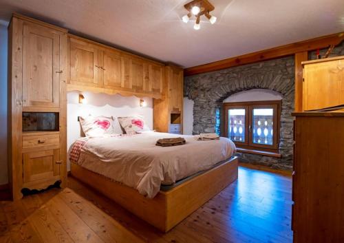 - une chambre avec un lit et un mur en pierre dans l'établissement Chalet vista Monte Bianco, à La Salle