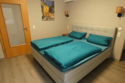 Una cama con almohadas azules en una habitación pequeña. en Paris, en Schwandorf