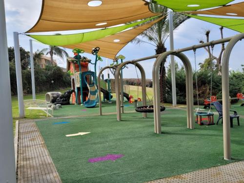 a park with a playground with swings and a canopy at סי מיה - דירות מהממות במתחם נאות גולף in Caesarea