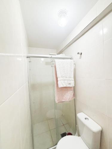 a white bathroom with a shower and a toilet at Apê Refúgio Urbano in Brasília