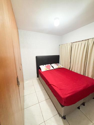 a small bedroom with a bed with a red blanket at Refúgio Urbano in Brasilia