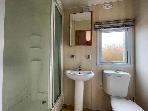 a bathroom with a sink and a toilet and a window at 6 Berth Dog Friendly Caravan In Hunstanton In Norfolk Ref 13014l in Hunstanton