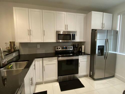 a kitchen with white cabinets and a stainless steel refrigerator at The Orchid Townhouse! 2B/2.5B in Miami Gardens