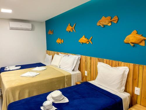 two beds in a room with fish on the wall at Pousada Villa Marceneiro Beach in Passo de Camarajibe