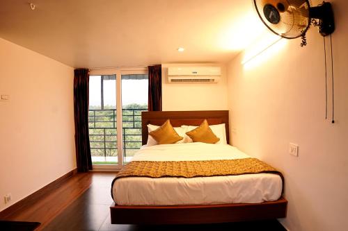 a bedroom with a bed with a window and a fan at GREEN MOUNT RESORTS in Malaiyāndipattanam
